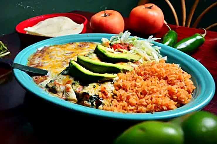 Combination plate topped with avocado slices and Mexican rice